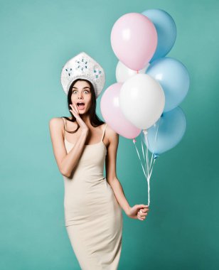 Balon ve hediye kutusu gri arka plan üzerinde tutan hayran kadın. Kameraya bakarak.