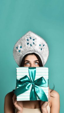 Geleneksel Rus şapkalı güzel bir kızın portresi. Elinde hediye kutusu var.