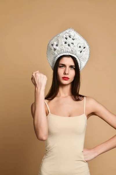 Femme mignonne montre poing à la caméra, porte un chapeau traditionnel russe kokoshnik chapeau, robe nue décontractée, montre la puissance des filles — Photo