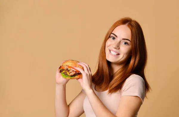 Close up retrato de uma jovem faminta comendo hambúrguer isolado sobre fundo nu — Fotografia de Stock