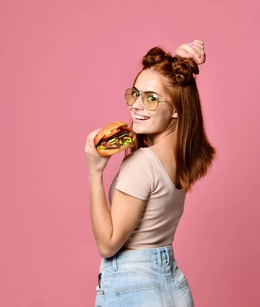 Yatay stüdyo çekim hamburger tutan genç ve güzel kadın — Stok fotoğraf