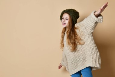 Örgü şapka ve kazak giyen mutlu küçük kız kış portresi.