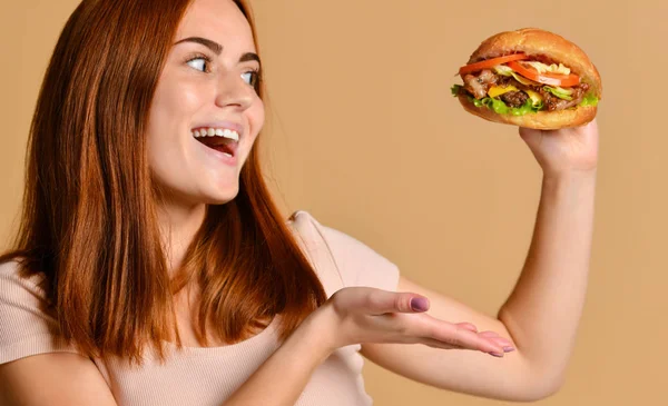 Εσωτερικη πορτρέτο του ένα πεινασμένο νεαρή γυναίκα τρώει burger απομονωμένη πέρα από το γυμνό υπόβαθρο — Φωτογραφία Αρχείου