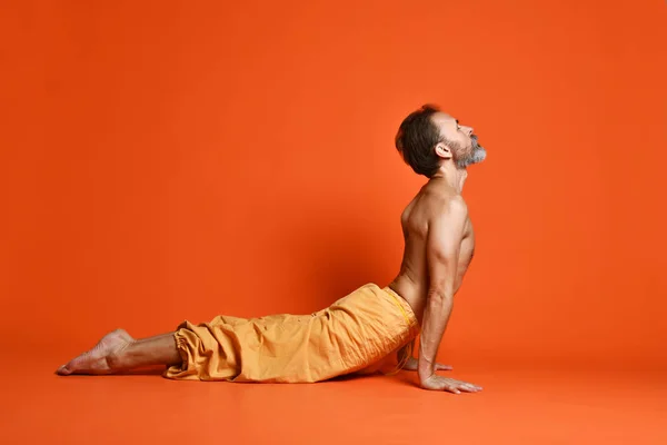 Fit old man doing yoga or pilates exercise. yle concept. Upward facing dog pose