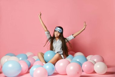 Uyku maskesi pembe arka plan üzerinde renkli balon ile eğleniyor sevimli beyaz seksi kadın