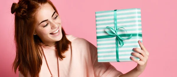 Portret van een vrij lachende roodharige meisje geschenkdoos houden en kijken, geïsoleerd op kleur roze achtergrond — Stockfoto