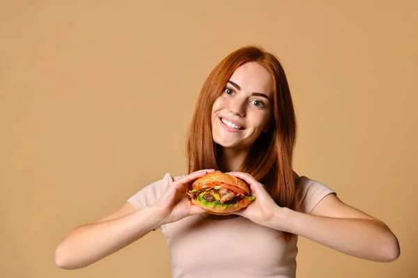 Portre aç genç bir kadının çıplak arka plan üzerinde izole hamburger yeme kapatmak — Stok fotoğraf