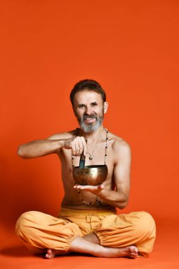 bir gri sakal yogi şarkı kase tutarak fiziksel görünüm olarak iyi olan yaşlı adam