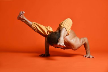 Turuncu arka planı germe yapıyor yaşlı adam pratik yoga egzersizleri