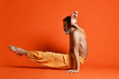Turuncu arka planı germe yapıyor yaşlı adam pratik yoga egzersizleri