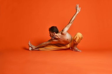 Turuncu arka planı germe yapıyor yaşlı adam pratik yoga egzersizleri