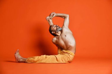 Turuncu arka planı germe yapıyor yaşlı adam pratik yoga egzersizleri