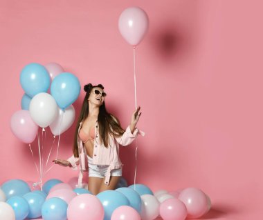 Renkli balonları olan güzel bir model parti kızı. Stüdyoda poz veriyor. Pink 'te..