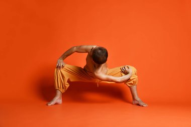 Turuncu arka planı germe yapıyor yaşlı adam pratik yoga egzersizleri