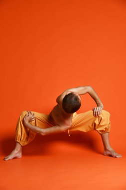 Turuncu arka planı germe yapıyor yaşlı adam pratik yoga egzersizleri