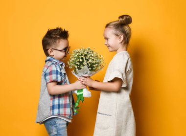 Küçük şirin şık çocuk papatyalar bir buket onun kız sarışın kız verir. bir çift romantik fotoğraf.