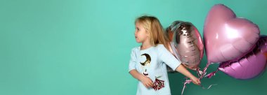 Küçük kız, kalp şeklinde pembe hava balonlarıyla eğleniyor..