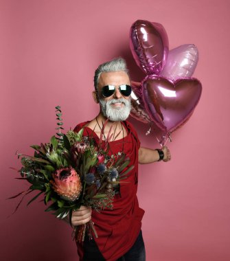 Balonları ve çiçekleri olan orta yaşlı bir adam..
