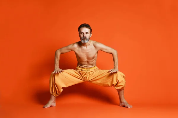 Retrato de hombres yoguis haciendo ejercicio de yoga sobre esterilla negra, respirando y realizando bloqueo abdominal ascendente, Uddiyana Bandha . — Foto de Stock