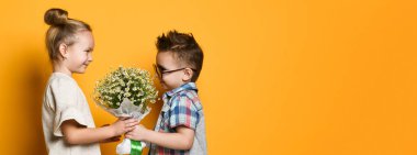 Küçük şirin şık çocuk papatyalar bir buket onun kız sarışın kız verir. bir çift romantik fotoğraf.