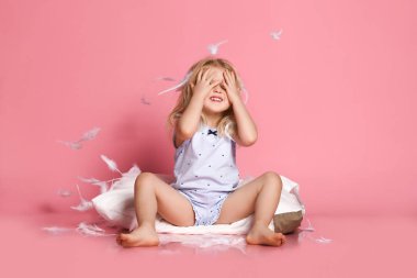 Yastığın üzerinde oturan güzel küçük kız. Stüdyo çekimi