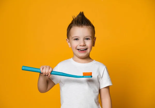 Sarı arka planda diş fırçası tutan küçük bir çocuğun portresi. — Stok fotoğraf