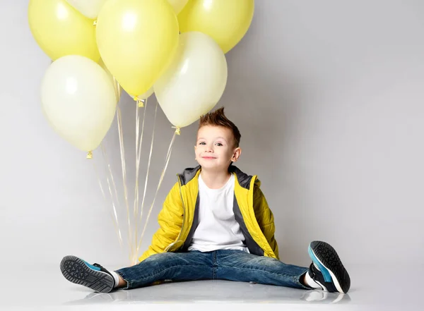 Diz üstü beyaz arka plan üzerinde kalan balon demet tutan çocuk — Stok fotoğraf