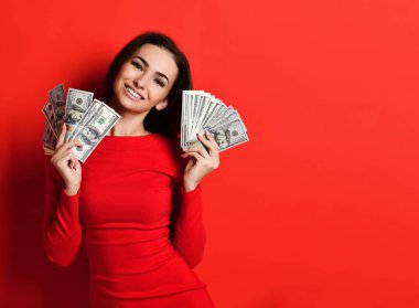 Kırmızı elbiseli genç ve güzel bir kadın bir sürü para banknotunun arkasına saklanıyor.