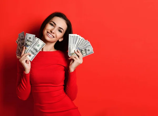 Young pretty woman in red dress hiding behind bunch of money banknotes — Stock Photo, Image