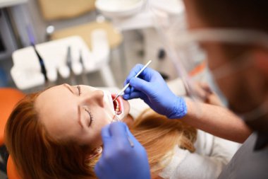 Diş hekimi kadın ağzını temizlemeye başlıyor