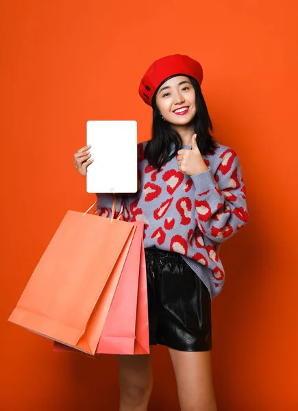 Jonge aziatische vrouw met boodschappentassen op kleur achtergrond — Stockfoto