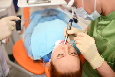 Diş hekimi kadın ağzını temizlemeye başlıyor