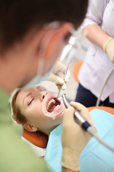 Diş hekimi kadın ağzını temizlemeye başlıyor