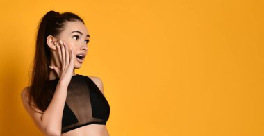 Heyecanlı güzel bir kadın büyük bir sevinçle şaşırmış görünüyor. Kız spor bir bluz giyiyor..