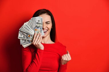 Yüzünün yarısını 100 dolarlık bir hayranla kaplayan, kırmızı elbiseli, sevimli, hassas, çekici ve güzel bir kızın portresi.