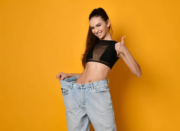 Beautiful young woman with big jeans — Stock Photo, Image