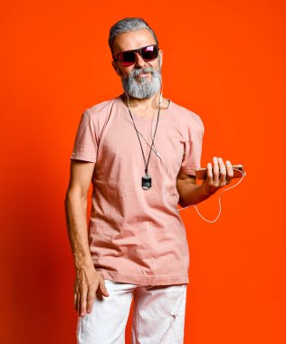 Kulaklıkla müzik dinleyen yaşlı kel bir adamın görüntüsü.