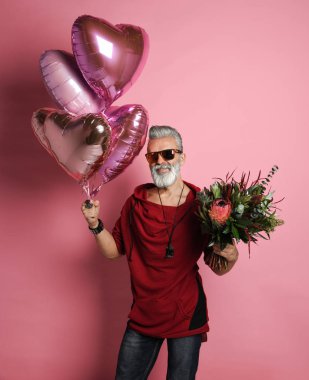 Balonları ve çiçekleri olan orta yaşlı bir adam..