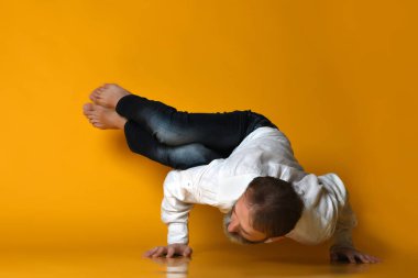 Yaşlı adam yoga yapıyor, sarı arka planda esneme egzersizleri yapıyor.