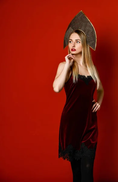 Прекрасна сексуальна блондинка в традиційному капелюсі кокошника, оксамитова святкова сукня на червоному тлі., — стокове фото