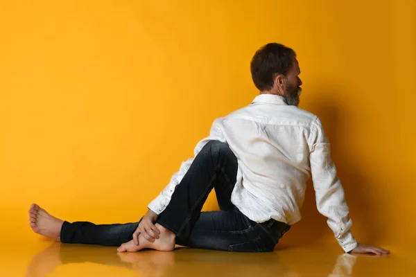El hombre mayor practica yoga en ropa formal de oficina. Aislado sobre un fondo amarillo. — Foto de Stock