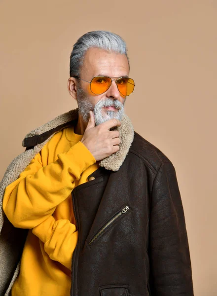 Retrato de un hombre adulto con barba y bigote en un abrigo de cuero y una boina, una mirada severa, el estudio sobre un fondo marrón-azul — Foto de Stock