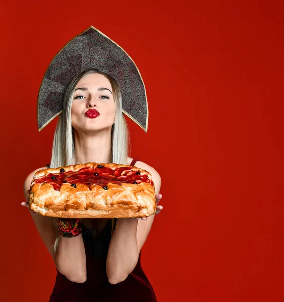 Portrait of a young beautiful blonde in headscarf holding a delicious homemade cherry pie. — Stock Photo, Image