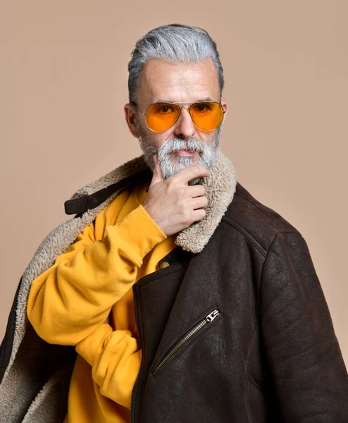 Retrato de um homem adulto com uma barba e bigode em um casaco de couro e uma boina, um olhar severo, o estúdio em um fundo marrom-azul — Fotografia de Stock