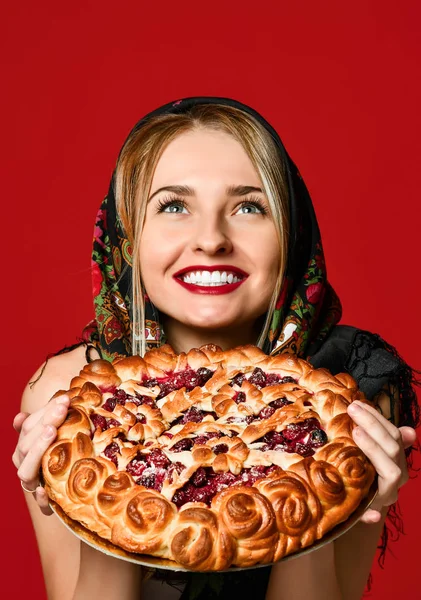 Retrato de uma jovem bela loira em lenço de cabeça segurando uma deliciosa torta de cereja caseira. — Fotografia de Stock