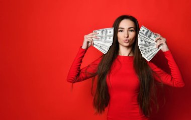 Kırmızı elbiseli genç ve güzel bir kadın bir sürü para banknotunun arkasına saklanıyor.