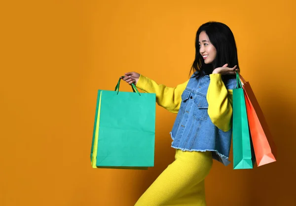 Молода азіатка з сумками на кольоровому фоні — стокове фото