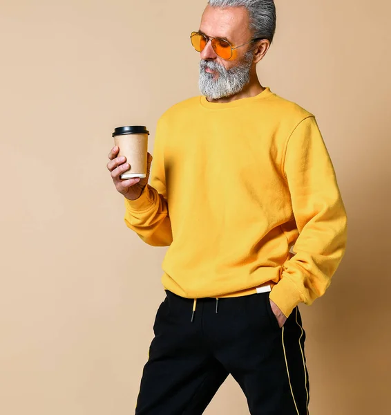Toma de un jubiloso anciano sosteniendo una taza de café blanco y mirando hacia otro lado cámara — Foto de Stock