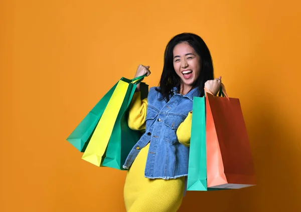 Jeune femme asiatique avec des sacs à provisions sur fond de couleur — Photo