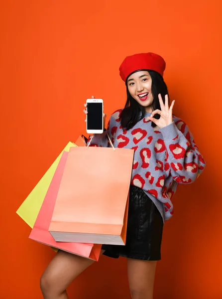 Молода азіатка з сумками на кольоровому фоні — стокове фото
